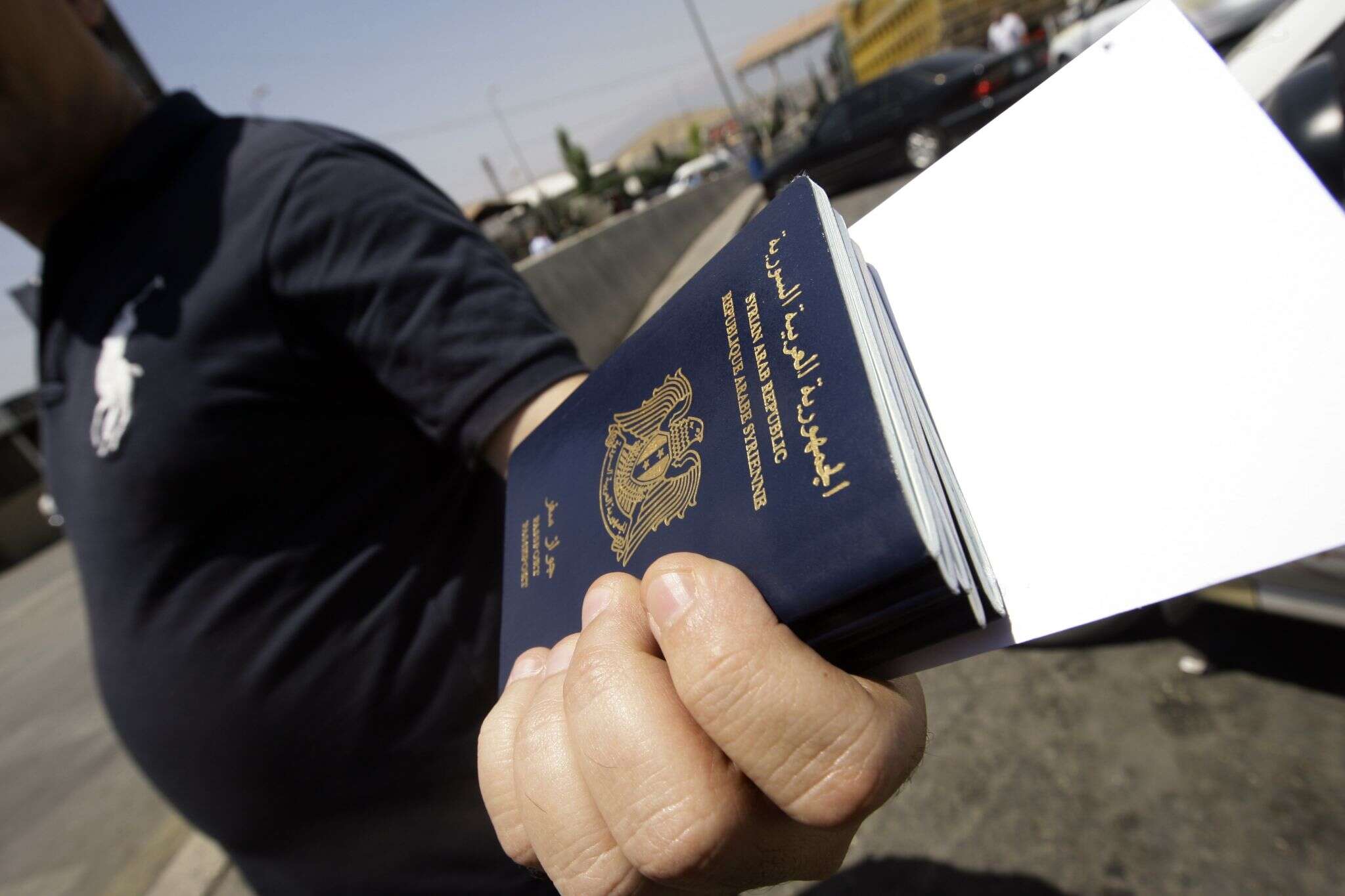 شخص يحمل مجموعة جوازات سفر - شروط دخول السوريين إلى لبنان