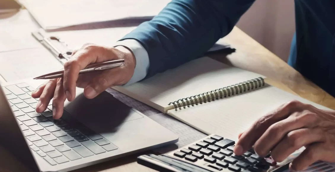 رجل يعمل على الحاسوب والآلة الحاسبة