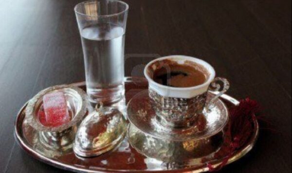 فنجان قهوة تركي مع كاس ماء وقطعة رمن راحة الحلقوم من عادات تقديم القهوة التركية